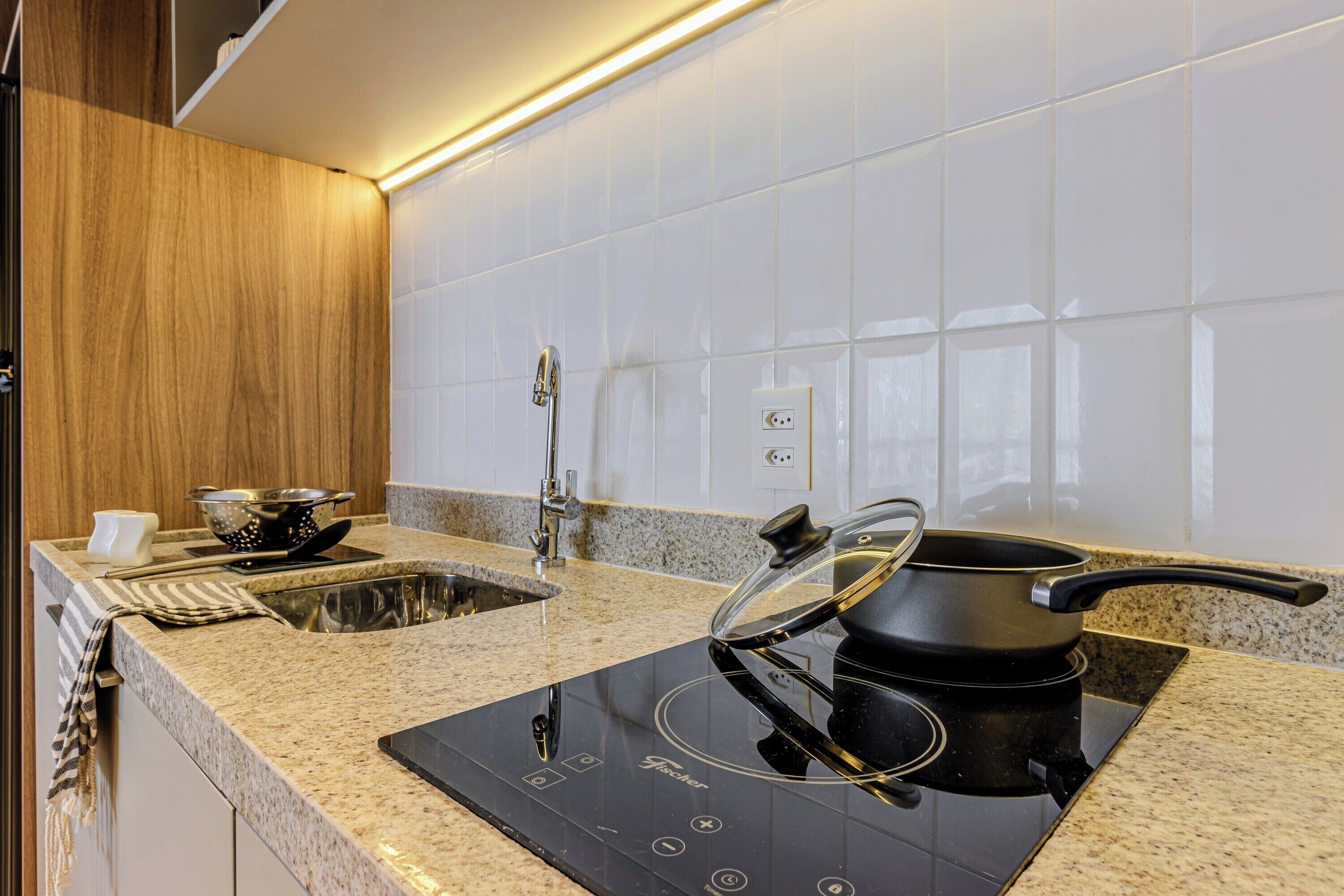 Una cocina moderna con estufa integrada, un lavamanos y un armario de madera.