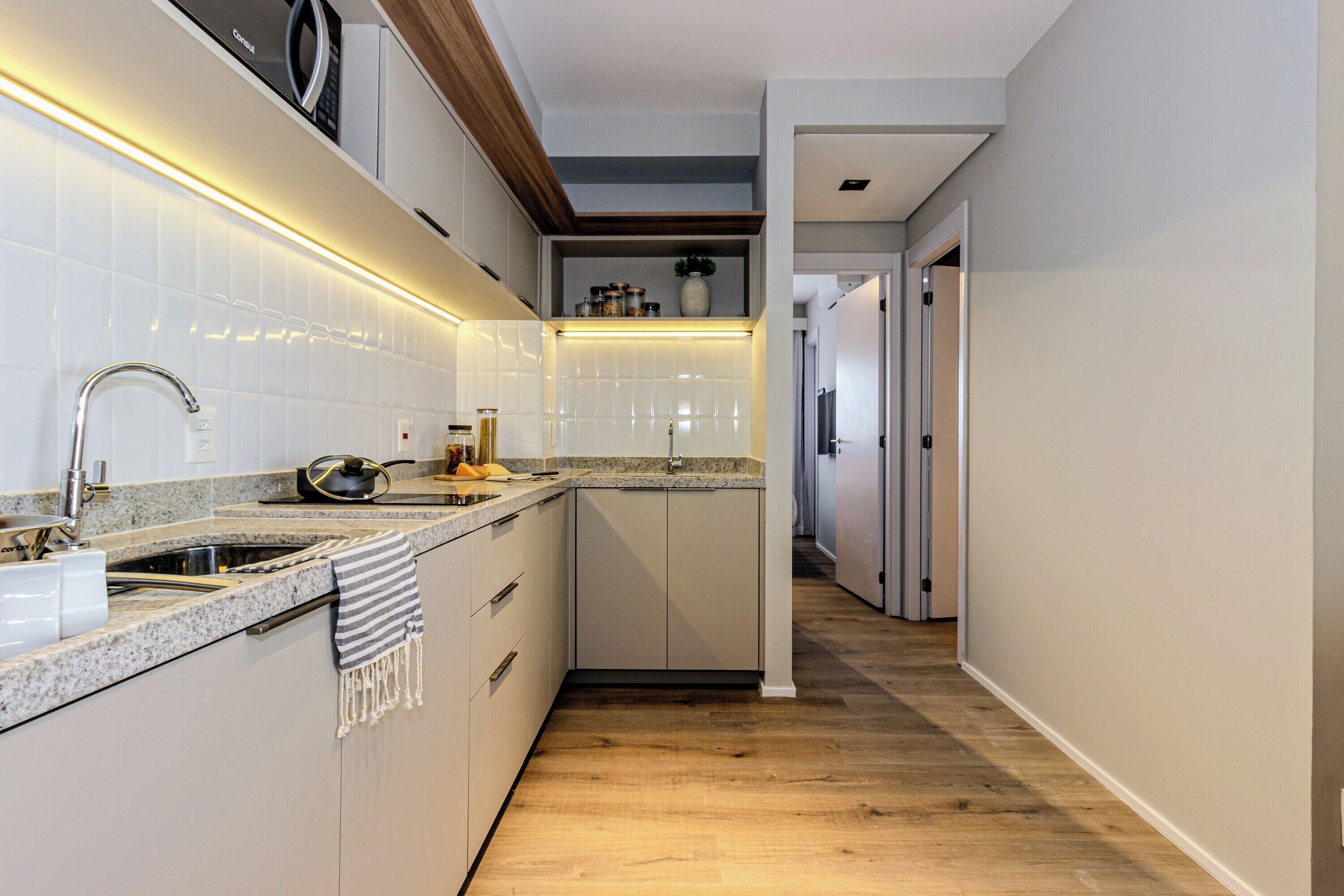 Een moderne keuken met witte kasten, een granieten aanrechtblad en een houten vloer.