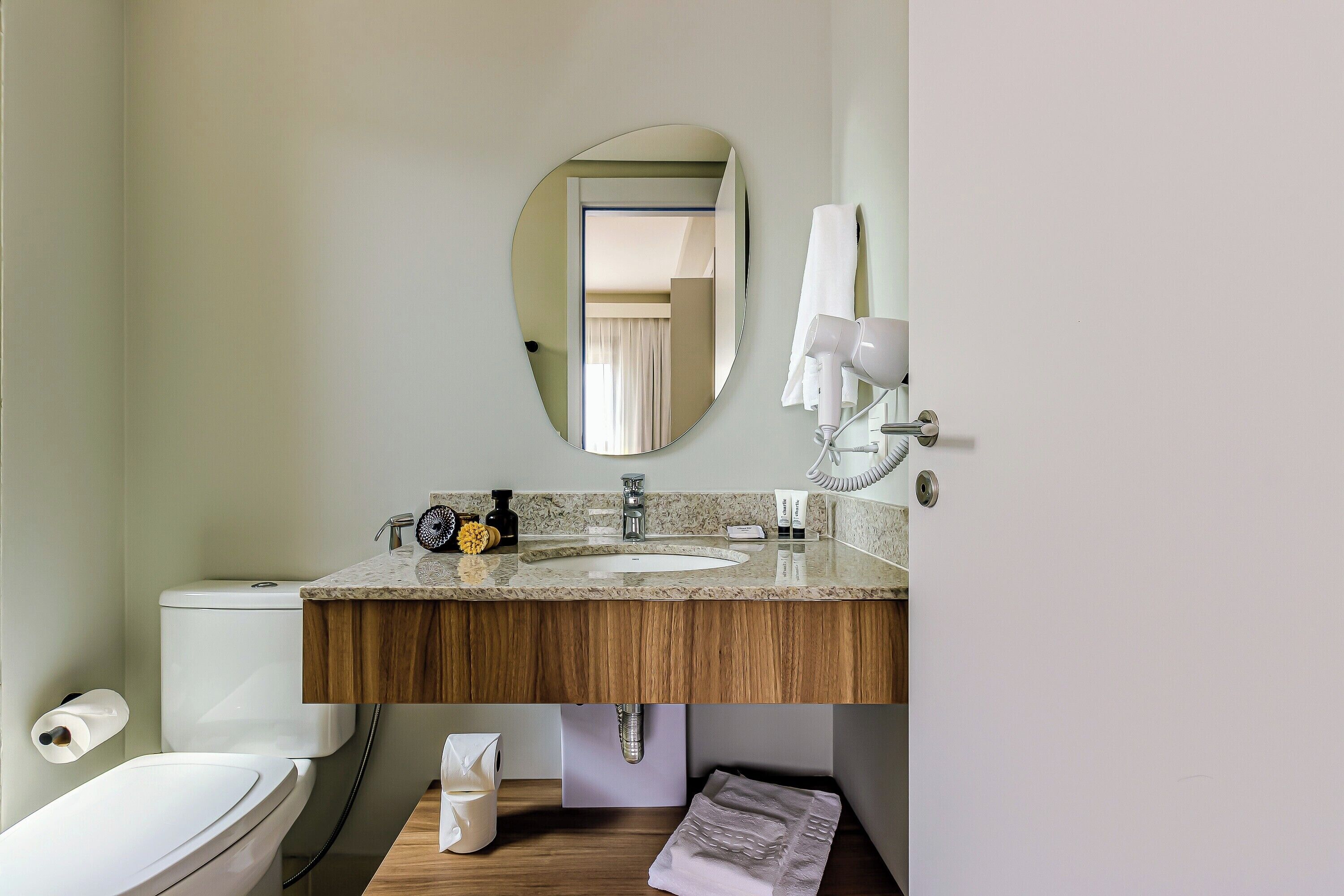 A bathroom with a toilet, sink, and mirror.