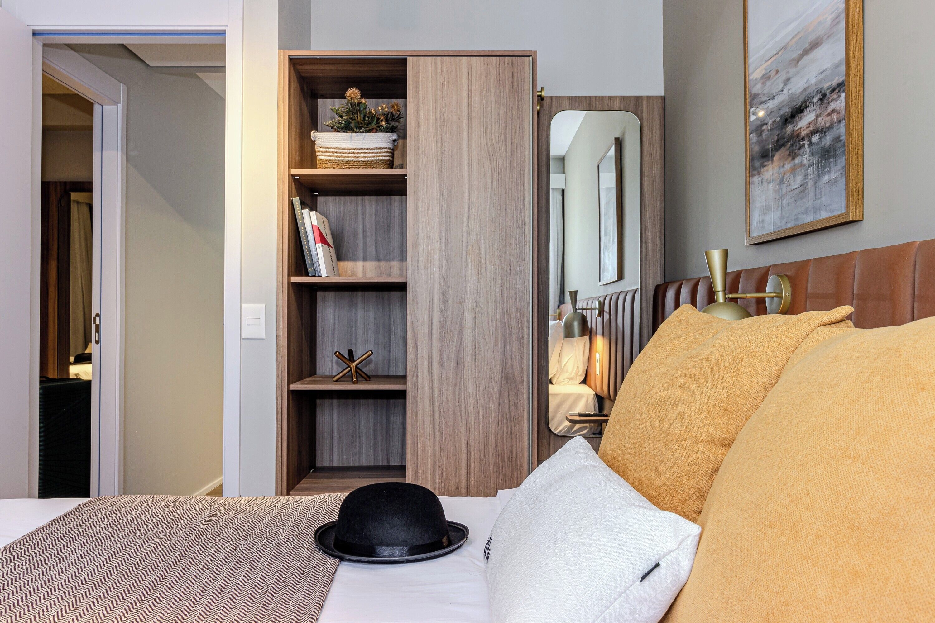 Una habitación de hotel con una cama, un armario, un espejo y un cuadro en la pared.