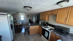 Una cocina compacta con refrigerador, estufa, microondas y armarios de madera.