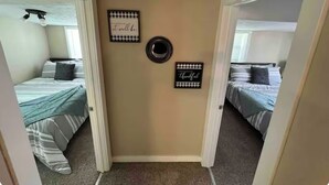 Un pasillo estrecho con dos habitaciones, cada una con una cama y un ventanal.