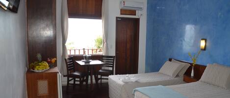 A hotel room with two beds, a dining area, and a window with curtains.