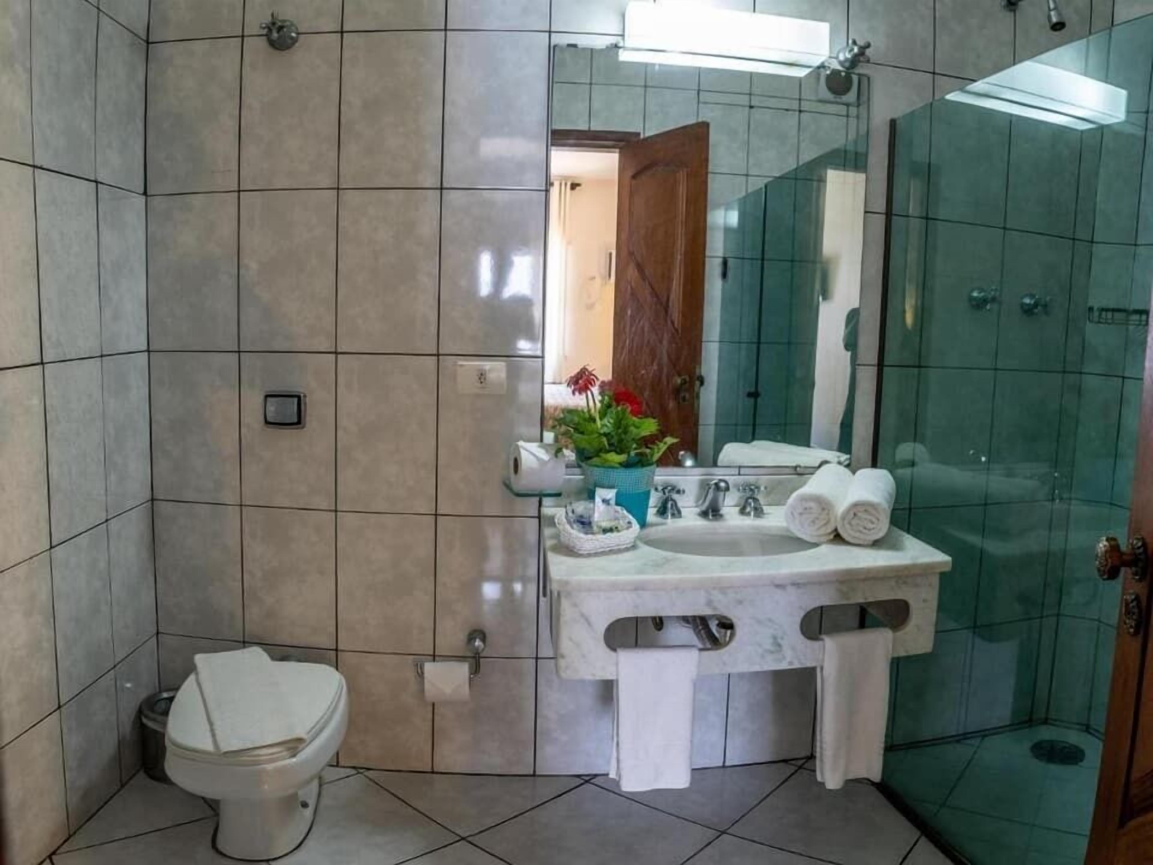 Ein Badezimmer mit Toilette, Bidet, Waschbecken und einer Duschkabine aus Glas.