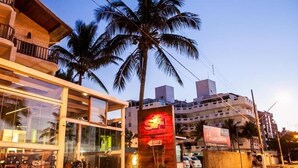 A building with a glass facade, palm trees, and a sign with a red logo.