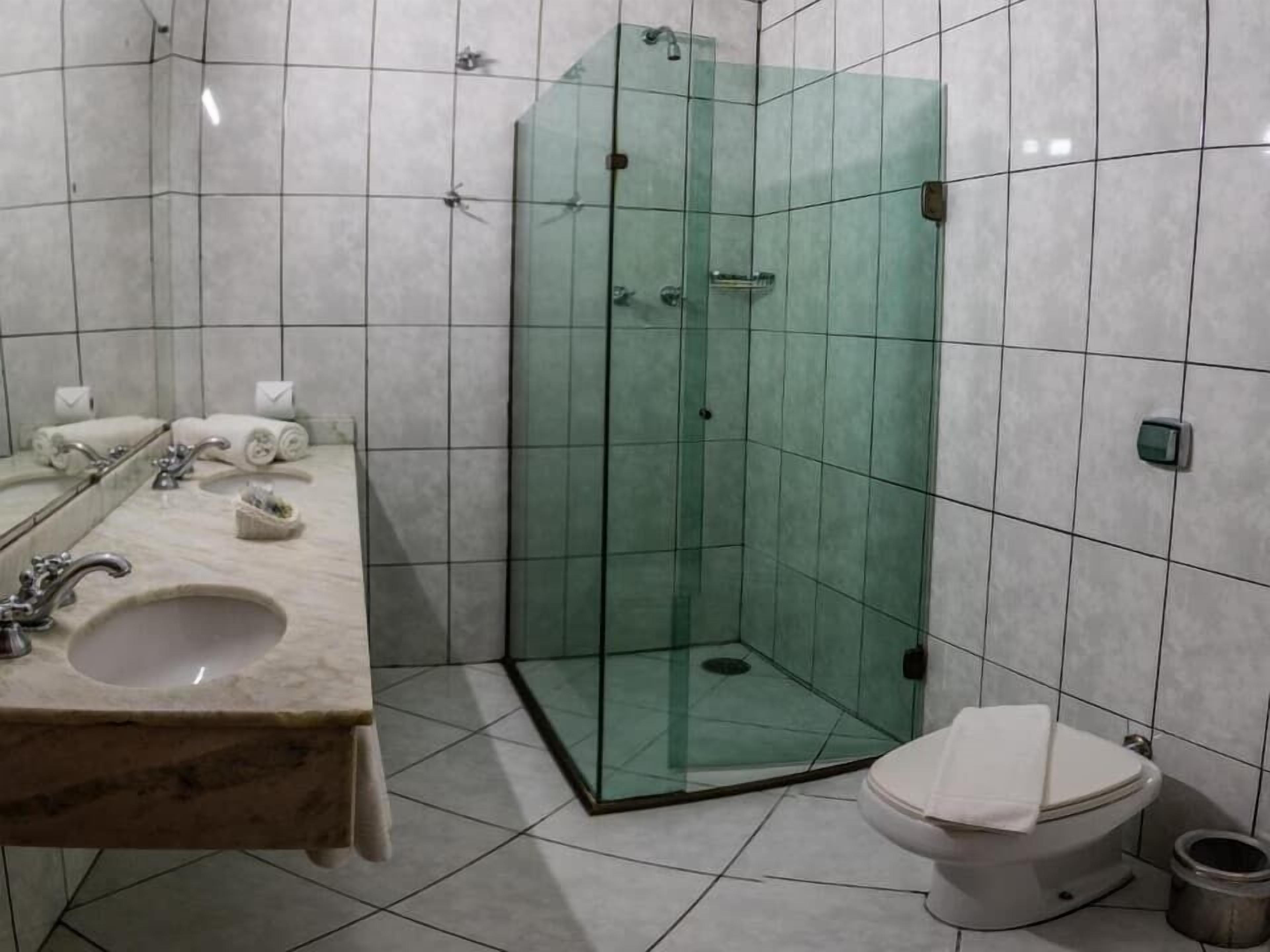 A bathroom with a glass-enclosed shower, a sink with a marble countertop, and a toilet.