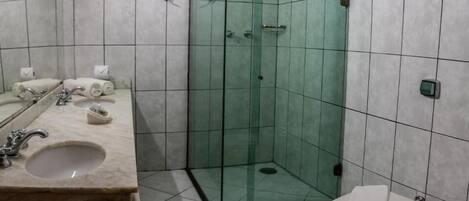 A bathroom with a glass-enclosed shower, a sink with a marble countertop, and a toilet.