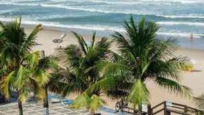 A beach with palm trees, a sandy shore, and waves crashing onto the beach.
