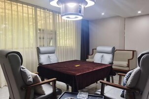 Un salón de conferencias con una mesa rectangular, cuatro sillas y una lámpara moderna.