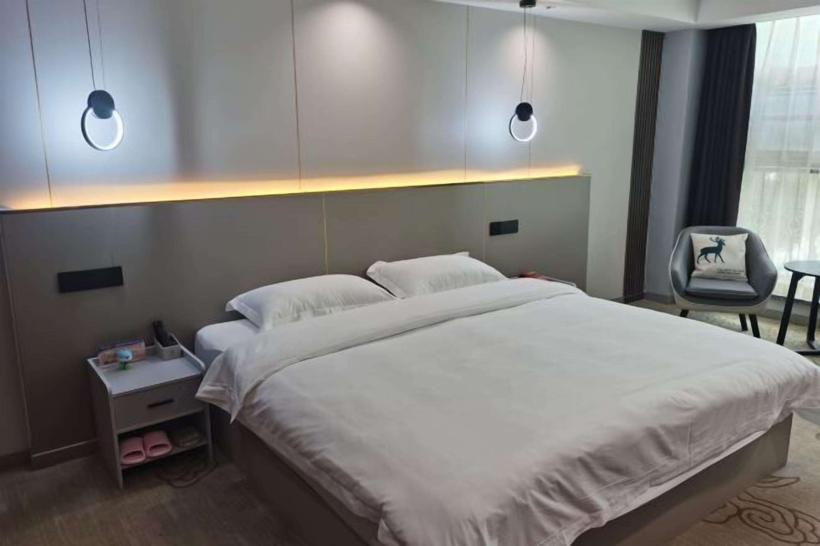 A modern hotel room with a large bed, bedside tables, and a chair.