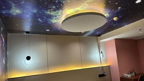A hotel room with a bed, a desk, and a wall with a galaxy-themed ceiling. - Jialing Bandao Hotel (Wusheng)