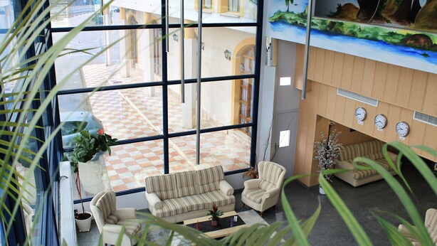 A lobby with a checkered floor, a sofa, a chair, a coffee table, and a fireplace. - Hotel Los Barruecos by Croma (Malpartida de Cáceres)