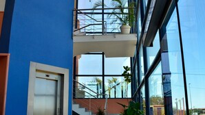 A modern building with a blue exterior, a glass elevator, and a staircase with potted plants. - Hotel Los Barruecos by Croma (Malpartida de Cáceres)