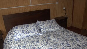 A bed with a floral-patterned bedspread and two pillows. - El Refugio de la Cuenca (Puerto Octay)
