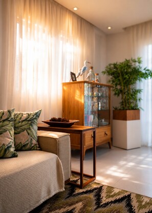 A modern living room with a sofa, a wooden cabinet with glass doors, and a large potted plant.
