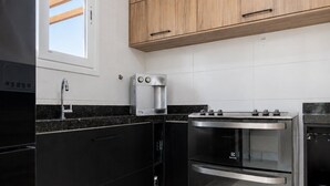 A modern kitchen with black cabinets, a stainless steel oven, and a coffee machine.