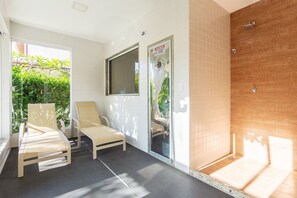 Un baño con ducha, un banco y una ventana.