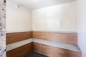 Baño con paredes de azulejos blancos, una sección inferior marrón y encimera de granito.