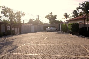 Un camino pavimentado que conduce a una entrada con puerta y un coche estacionado.