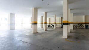 Eine großzügige Parkgarage mit Betonpfeilern und einem Fahrrad, das an der Wand steht.