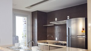 A modern kitchen with a stainless steel refrigerator, a gas stove, and a sink.