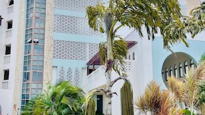 Un edificio moderno con una mezcla de estilos arquitectónicos, incluyendo una ventana arqueada destacada y elaborados celosías decorativas.