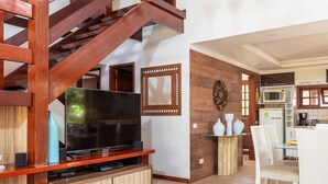A modern kitchen with a microwave, coffee maker, and a dining area with chairs and a table. - BZ03 House in a Club Condominium Steps from the Beach (Armação dos Búzios)