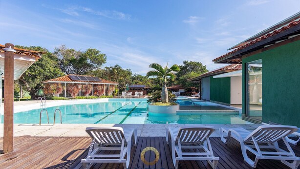 A swimming pool with lounge chairs and a wooden deck. - BZ03 House in a Club Condominium Steps from the Beach (Armação dos Búzios)
