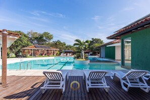 Una piscina con sillones de descanso y una terraza de madera.