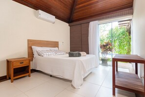 A bedroom with a wooden headboard, a bedside table, and a small wooden shelf. - 40m from the beach! Beautiful house with private pool BZ26 (Armação dos Búzios)