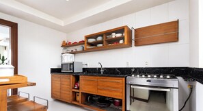 Una cucina moderna con mobili bianchi, un piano di lavoro nero, forno integrato e microonde.