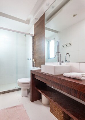 A modern bathroom with a glass shower enclosure, a white toilet, a wooden vanity with a mirror, and a white sink. - 40m from the beach! Beautiful house with private pool BZ26 (Armação dos Búzios)