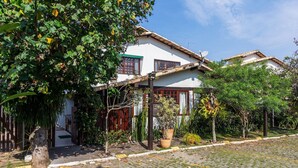Una casa tradicional con techo de tejas, antena parabólica y jardín con plantas en macetas.