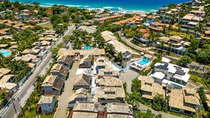 A coastal residential area with houses, a swimming pool, and a view of the ocean.