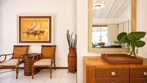 A room with wicker furniture, a framed painting, a mirror, and a plant.