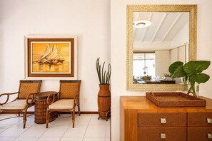 Una habitación con muebles de mimbre, un cuadro enmarcado, un espejo y una planta.