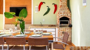 A dining area with a brick oven, a television, and a plant.