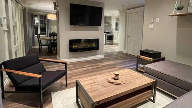 A modern living room with a fireplace, a sofa, a coffee table, and a TV mounted on the wall.