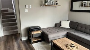 A modern living room with a grey sectional sofa, a wooden coffee table, and a staircase leading to another level.