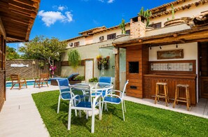 Eine Terrasse mit Pool, Sitzgelegenheiten im Freien und einer Grillplatz.