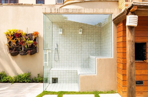 Zona de ducha con paredes de azulejos y un escalón pequeño para entrar.