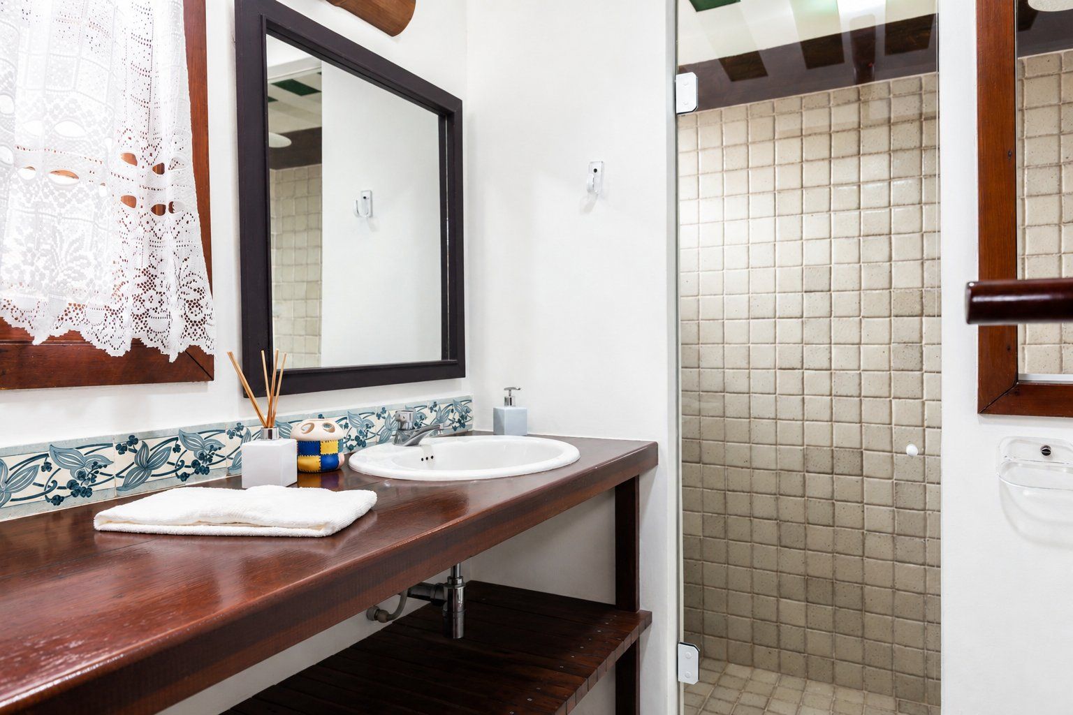 Une salle de bain avec un meuble-lavabo en bois, deux vasques, un miroir et un espace douche.