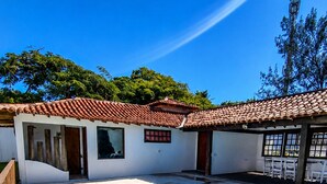 A swimming pool with tiled edges, a covered patio area, and a building with a tiled roof. - Bz34 House with Pool and Sauna 300 m from the beach! (Armação dos Búzios)