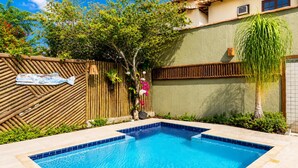 A swimming pool with a wooden fence, a small tree, and a tiled wall. - Bz34 House with Pool and Sauna 300 m from the beach! (Armação dos Búzios)