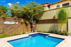 A swimming pool with a wooden fence, a small tree, and a tiled wall. - Bz34 House with Pool and Sauna 300 m from the beach! (Armação dos Búzios)