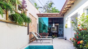 Un espace aménagé au bord de la piscine, dot é d’un sol carrelé, d’une piscine, de chaises longues et d’un patio couvert.