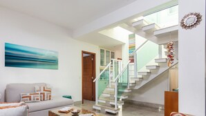 Un salon comprenant un canapé, une table basse et un escalier menant à l’étage supérieur.