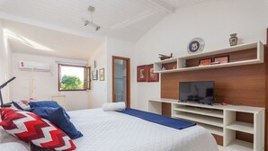 Une chambre à coucher avec un lit, une télévision et une étagère où sont exposés des objets décoratifs.