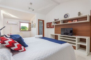 A bedroom with a bed, TV, and a shelf with decorative items.