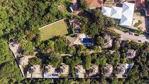 Vue aérienne d’un complexe hôtelier comprenant plusieurs bâtiments de style bungalow, une grande piscine et une végétation luxuriante.